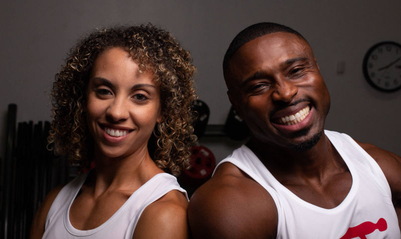 Teddy and a partner performing cable exercises with big smiles